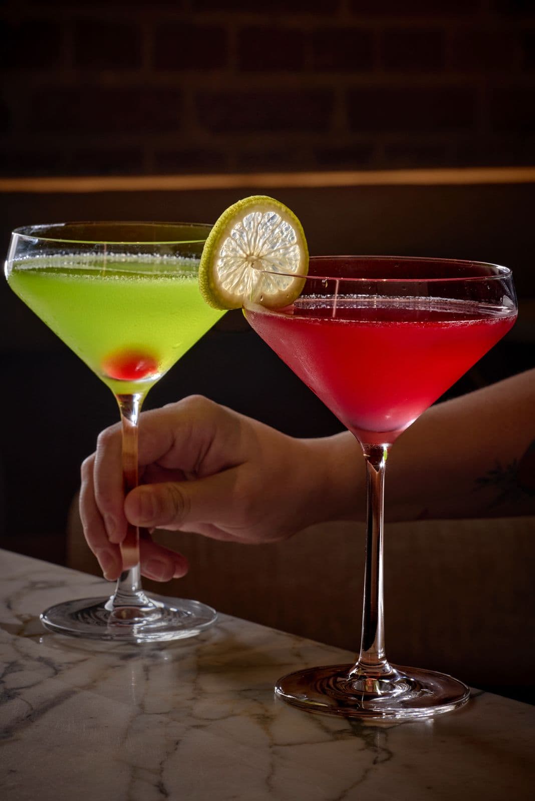 A Mexican Slipper and a Cosmopolitan in martini glasses on the marble bar