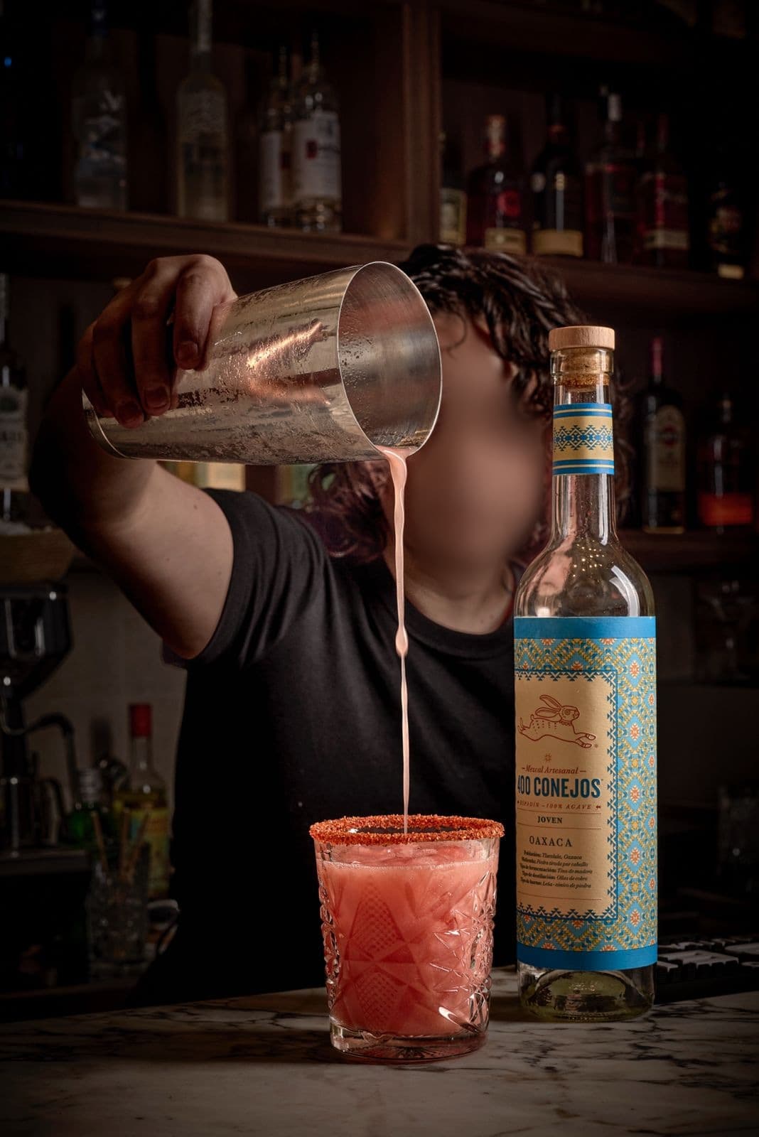 Mezcalita Tío Teddy with a chile rim, served next to a bottle of mezcal