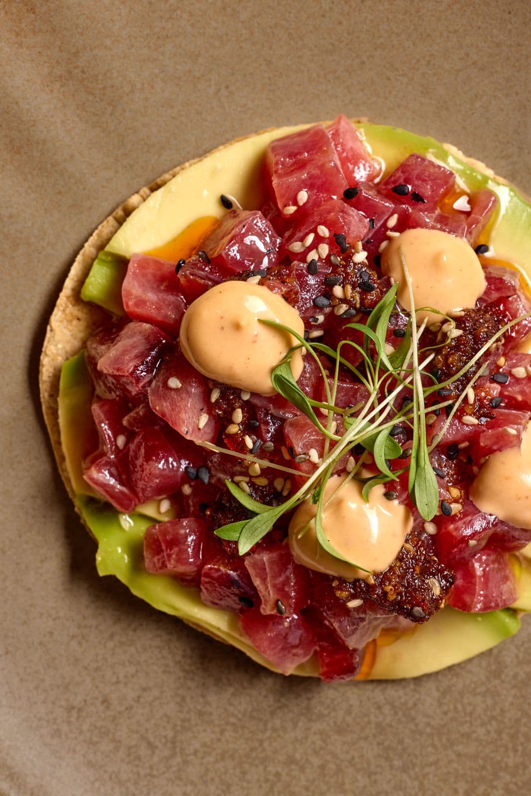 Tostada topped with diced tuna, avocado, chipotle mayo and sesame